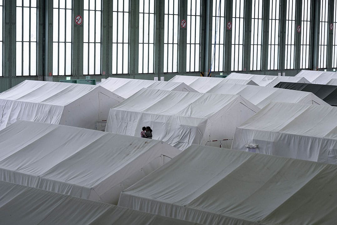 2015年12月11日,柏林, 德國政府與志願組織合作，於廢棄了的滕珀爾霍夫機場 (Templehof) 設立難民營。圖為一名婦女帶著子女經過帳蓬。攝：Ashley Gilbertson / VII Photo for UNICEF