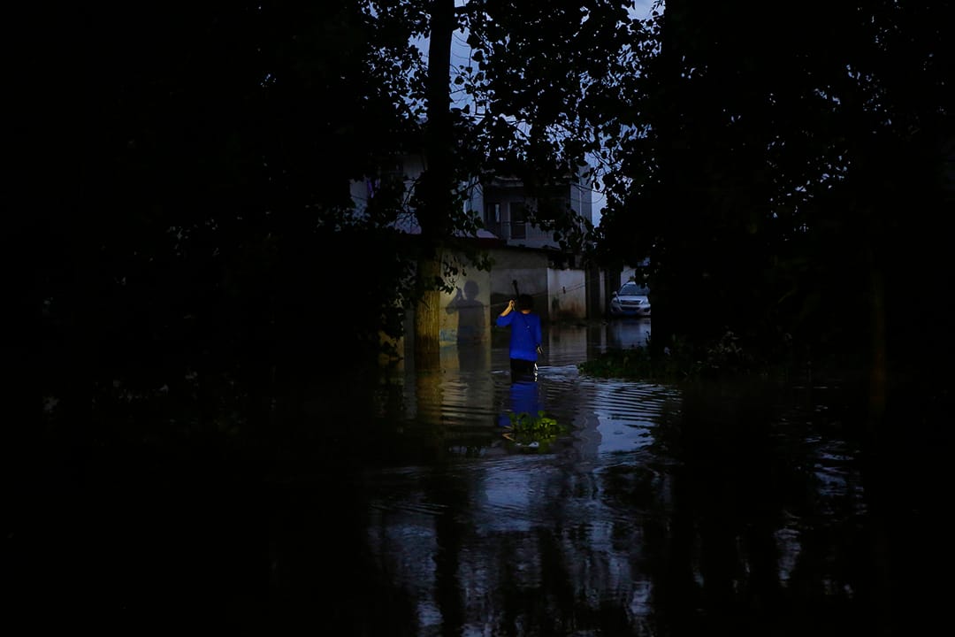 中國武漢,河水缺堤,一名村民在洪水中走路。