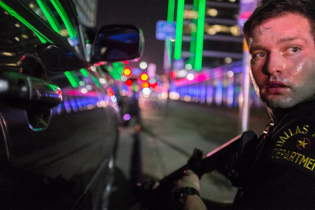 达拉斯反对警察暴力对待黑人游行中有枪手狙击射杀警员,Robert Moore蹲在一个持枪警察背後,与他一同经历惊险时刻。