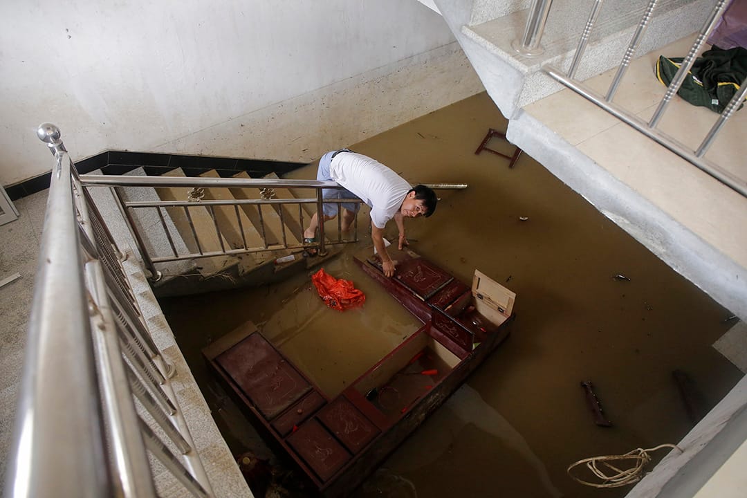 中國武漢,河水缺堤,一名村民在家中搜索被淹沒的財物。