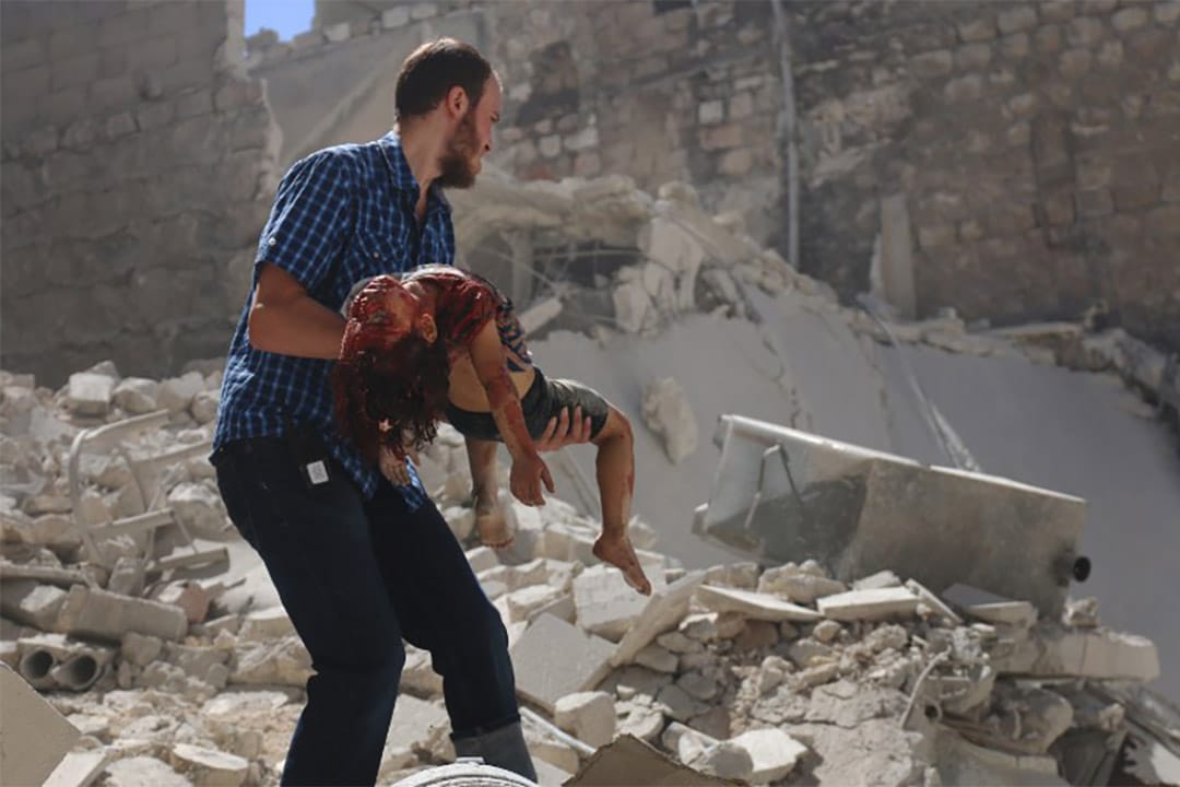 2016年7月25日，阿勒颇经历空袭后，一个叙利亚人从瓦砾中救出一个女孩。
