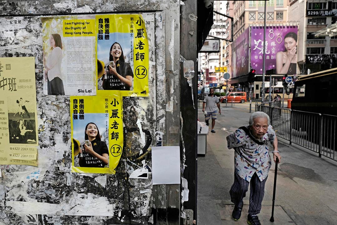 一名老人走過張貼著小麗民主教室宣傳單張的街道。