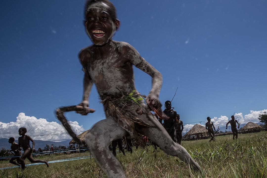 印尼,一个年轻的男孩在巴列姆谷文化节中奔跑着,模拟战斗情况。