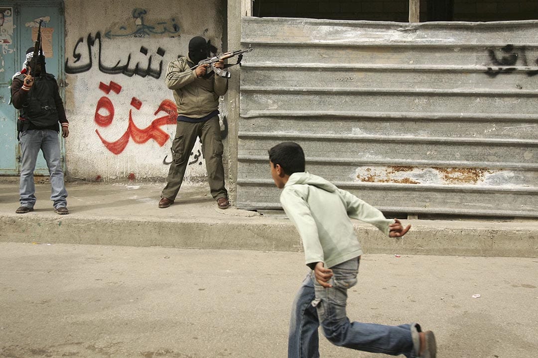 加沙地区,一名孩子在当地亲政府维和部队与哈马斯战士开火时逃跑。