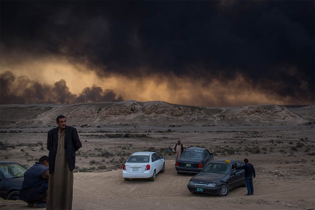 2016年11月9日，伊拉克盖亚拉，人们站在起火的油井附近。