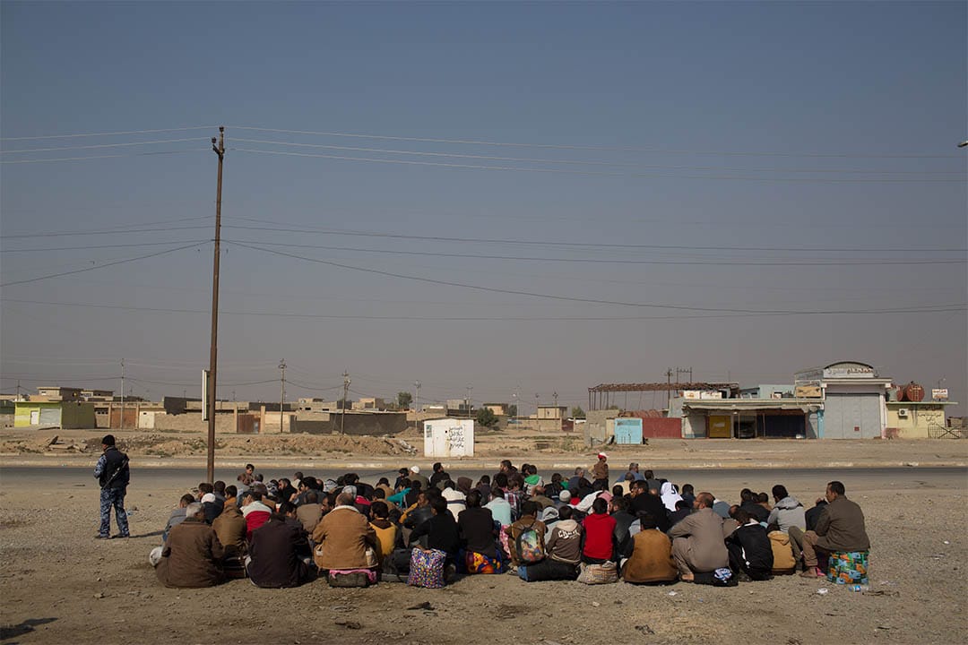 2016年11月7日，伊拉克高吉亚利，一群男士等待车辆前往国内流离失所者营地。