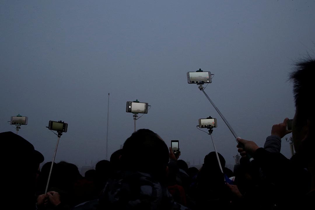 中國北京,市民在霧霾中為天安門廣場的升𣄃儀式拍照留念。