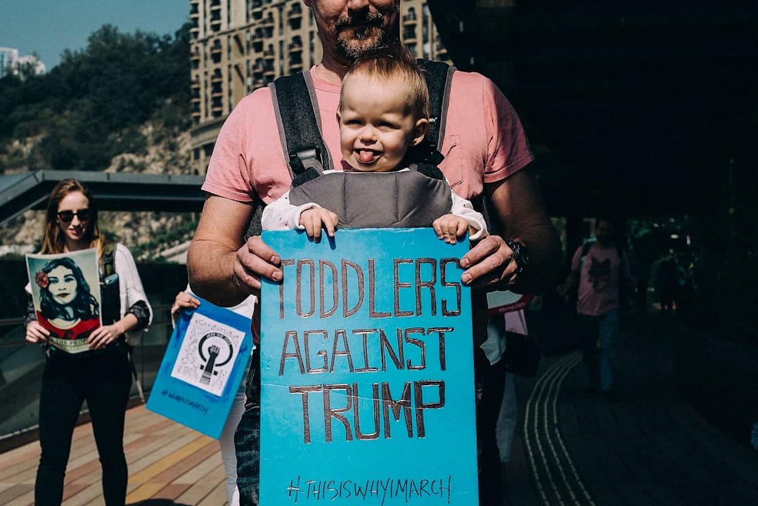 在澳门，一名父亲带同幼儿参与示威，并手持“幼儿反对特朗普”标语牌。