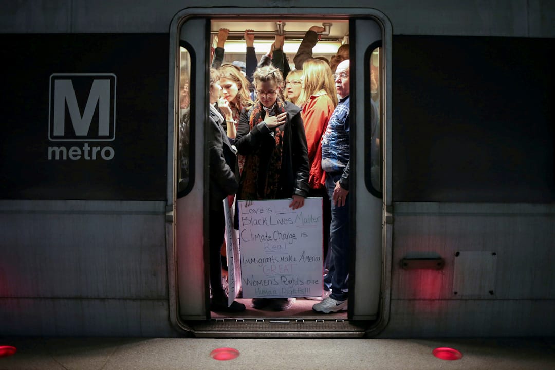 在美国华盛顿，拿着标语的女士正乘坐地铁前往示威区。