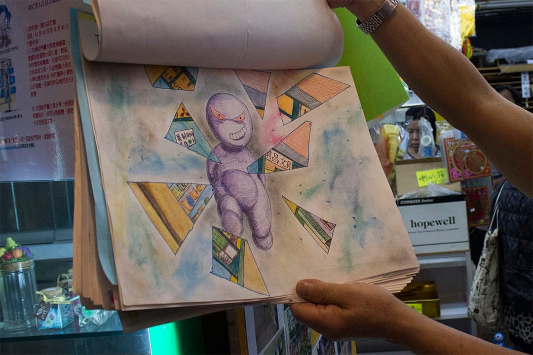 老闆羅先生翻開一張由街坊送贈的畫作,寓意領展破壞小店的生存空間。