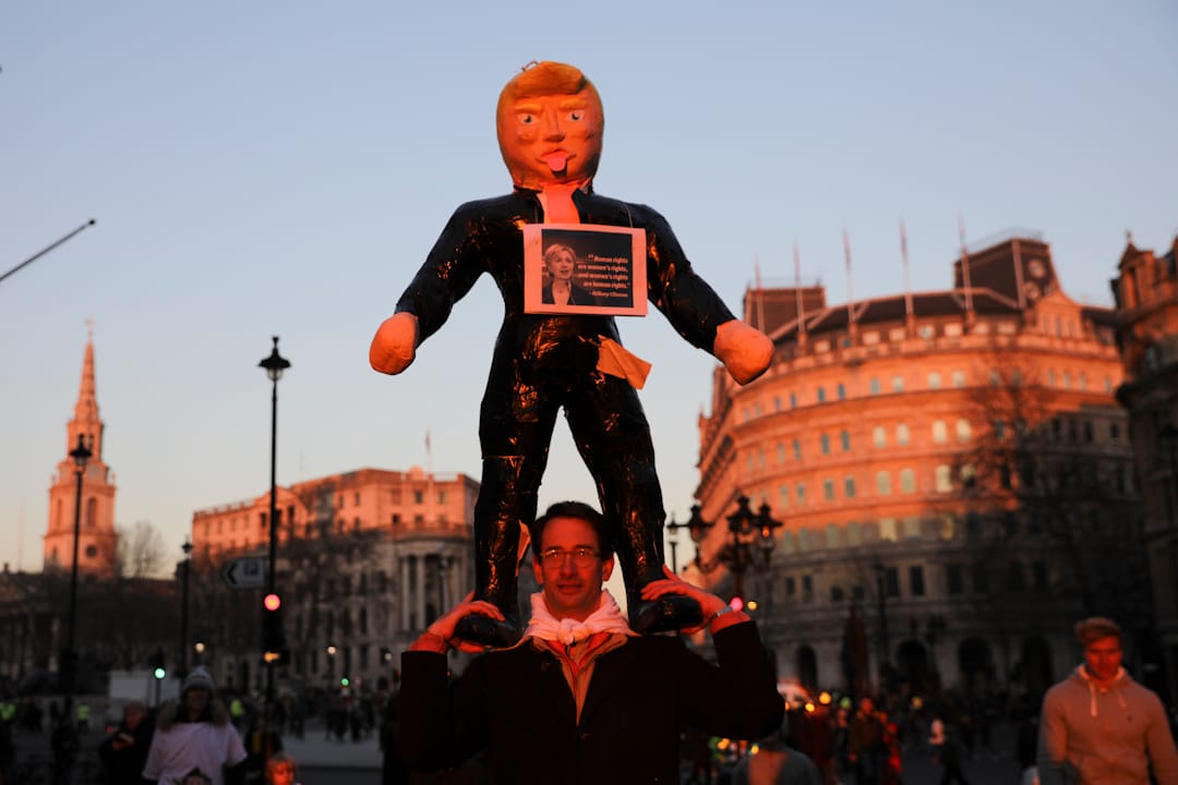 在英国伦敦，一名抗议者手持特朗普总统肖像在街上游走。