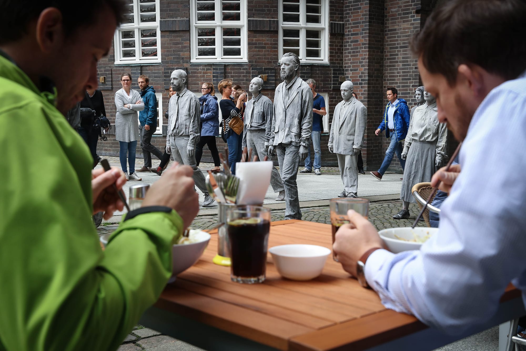 2017年7月5日，「1000 Figures」的參與者，走過漢堡市中心，經過一間戶外餐館。