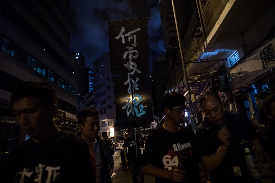 游行队伍前排举起了一支旗帜,黑布上写上 “何处招魂” 四字。