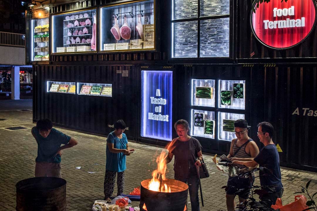 农历七月十四前夕,居民于启业邨街市外烧街衣,刚装修的街市,以货柜箱的形式设计大门。该区为旧 式公共屋邨,住了不少基层长者。