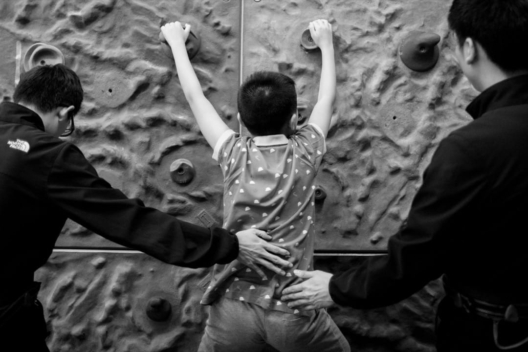 對只學了3個多月的天宇來說,沿著牆邊攀爬的熱身運動仍然有一定的難度,需兩位教練在旁協助。