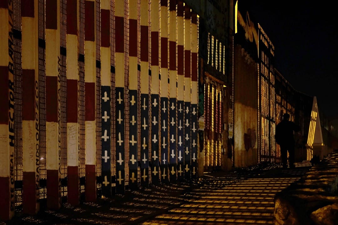 2018年4月5日,墨西哥蒂华纳,一名墨西哥人在墨美边境围栏旁走过。