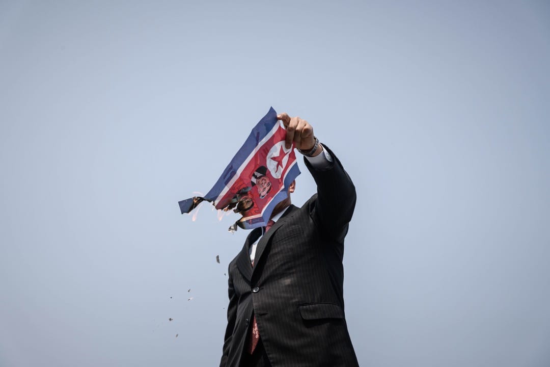 2018年4月27日,南韩坡州临津阁和平公园通往板门店非军事区的统一大桥检查站,一名反北韩示威者在焚烧北韩国旗。