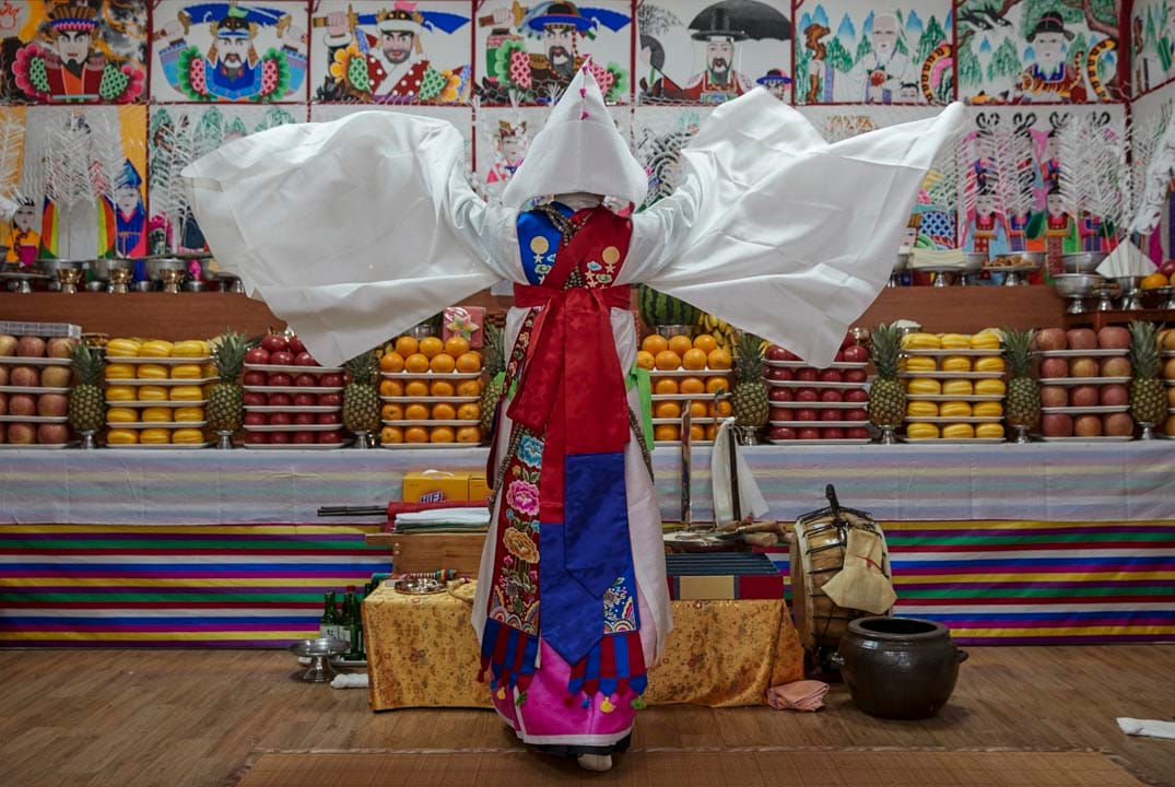南韓始興市,薩滿巫師Nunkotsunnyu正在進行「跳神」儀式,教徒相信儀式能夠帶來運氣,榮譽,健康及避免邪靈帶來災害。牆壁上貼滿神靈的畫作及護符避免邪靈干擾儀式。