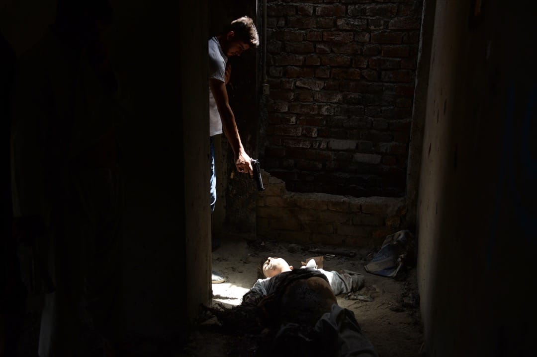 2014年7月17日，一名阿富汗情报人员用手枪指着叛乱者的身躯。当日武装组织塔利班于喀布尔国际机场发动恐袭，4名袭击者与阿富汗军警交火身亡，1名警察受伤。