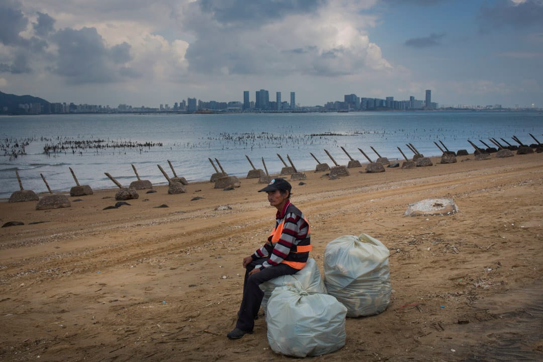 2018年8月20日，小金门海滩上布满轨条砦，一名海滩工作人员正在歇息，对岸为中国厦门市。