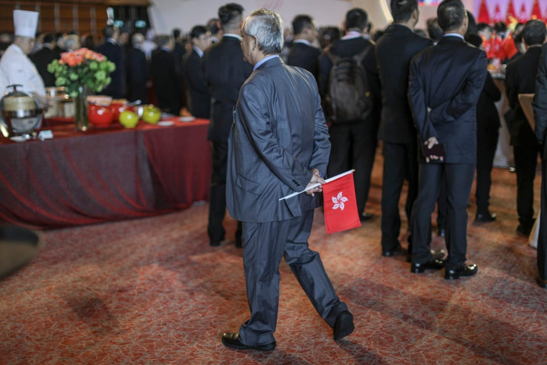 湾仔会展举行国庆酒会,一名参加者手持香港及中国国旗进场。