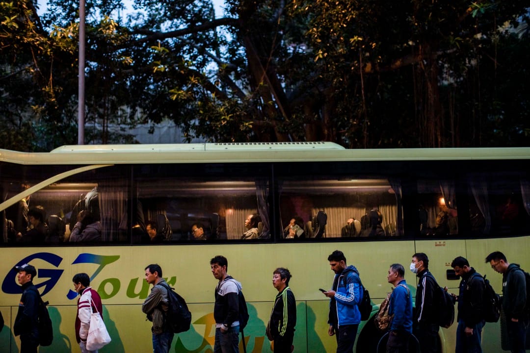 3月1日清晨,工人们如常到裕民坊游憩公园外,等候来接送他们到地盘工作的旅游巴士。