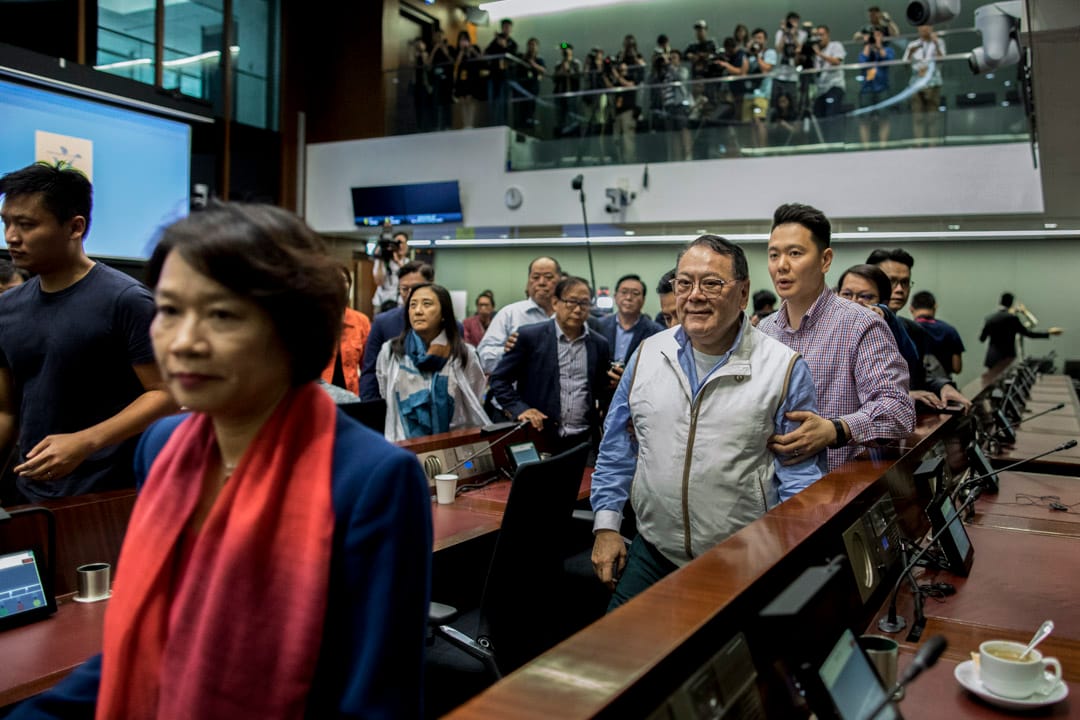 12:02PM - 经民联议员石礼谦在数名建制派议员护送下离开会议室。