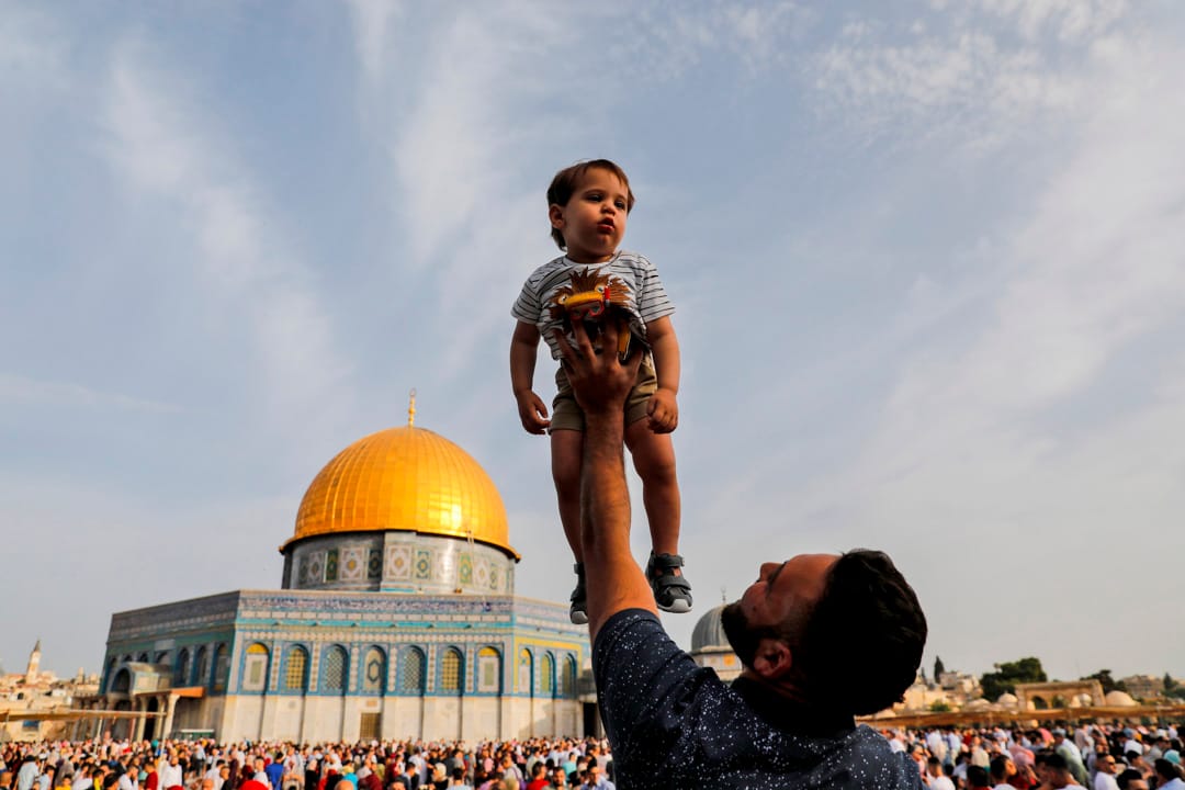 2019年6月5日,耶路撒冷老城阿克萨清真寺外,穆斯林们正做开斋节的清晨祈祷,一名父亲托起了他的孩子。