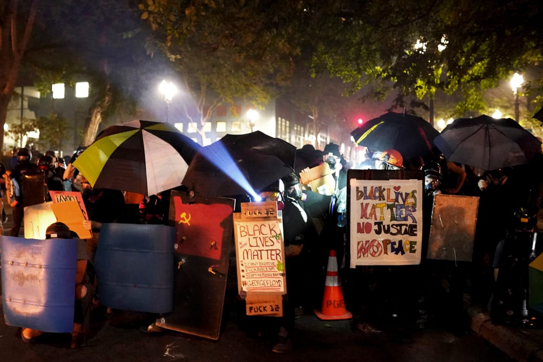 2020年7月21日，波特蘭示威者以傘及一些膠板築起防線，向警方推進。
