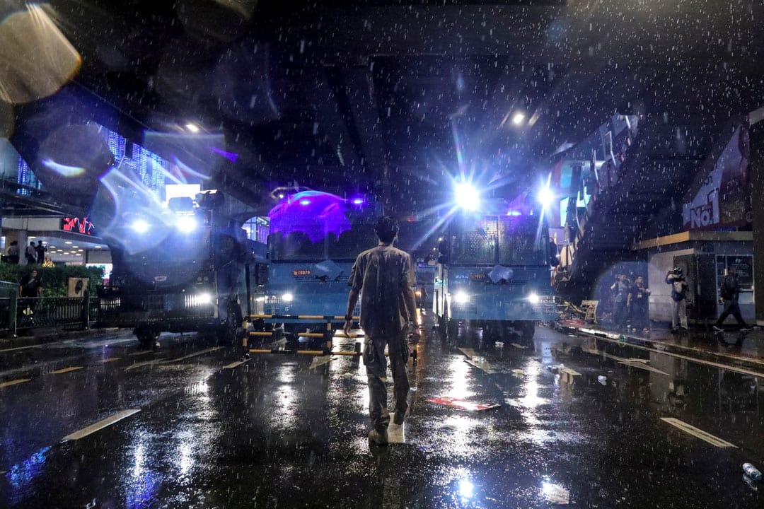 2020年10月16日泰国曼谷,一场反政府抗议活动中,一名男子走在马路中水砲车的前方。