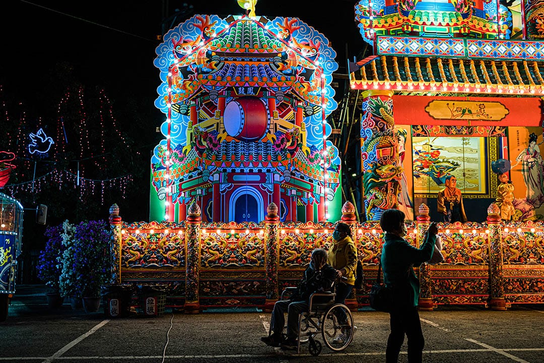 一位鎮上的長者由家人推著輪椅,前往祭典現場。