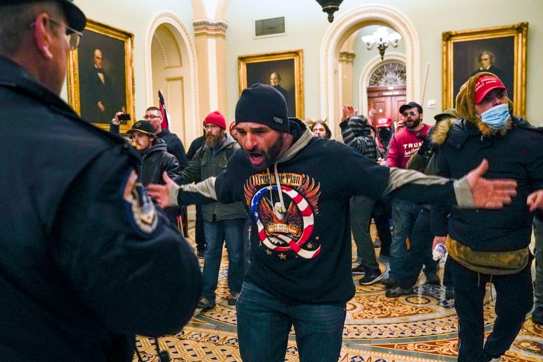2021年1月6日,美国国会,一名特朗普支持者在参议院会议厅外向一名国会警察示意。