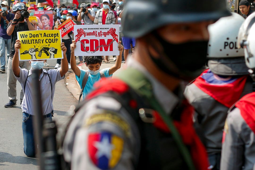 2021年2月19日缅甸仰光,反对军政府的示威游行中,缅甸示威者举著牌子跪在防暴警察面前。