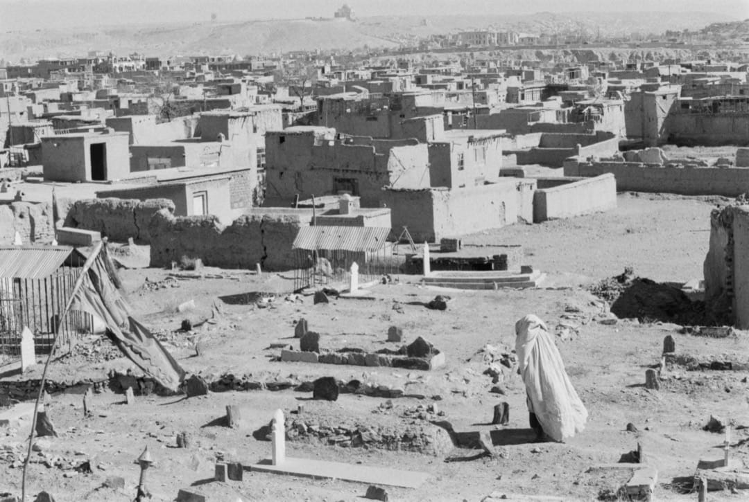 一名穿罩袍的女子在阿富汗一个墓地走过。