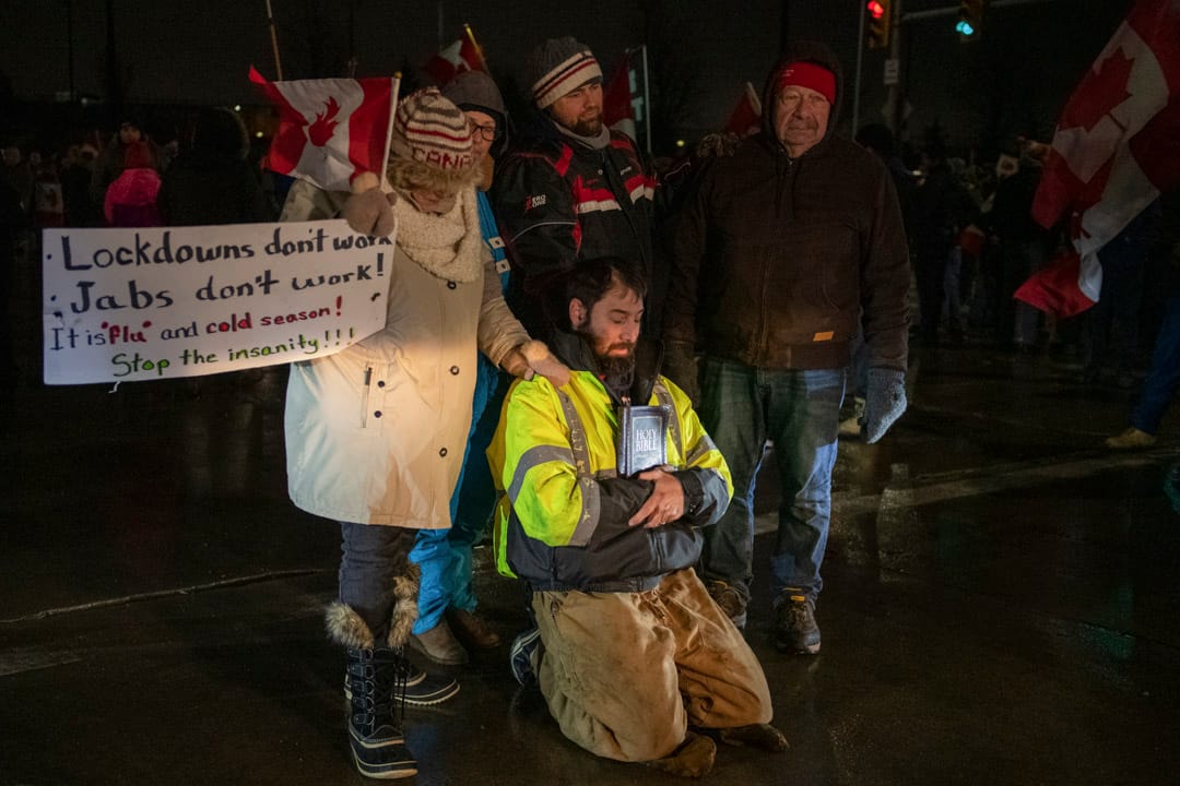 2022年2月11日,加拿大安大略省温莎市,数名“自由车队”反疫苗示威的参与者在路中心祈祷,连同其他示威者一起堵塞连接美国的大使桥。