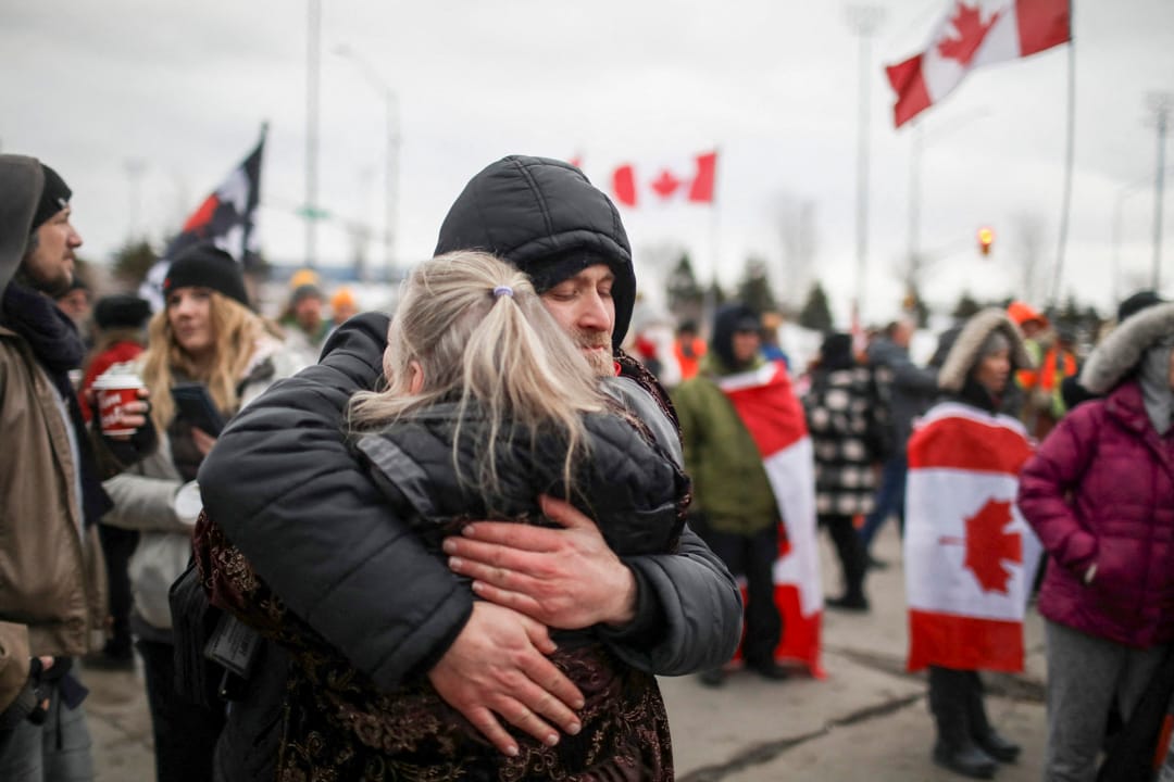 2022年2月10日,加拿大安大略省温莎市,“自由车队”反疫苗示威参与者堵塞通往美国的大使桥,两名示威者在拥抱。