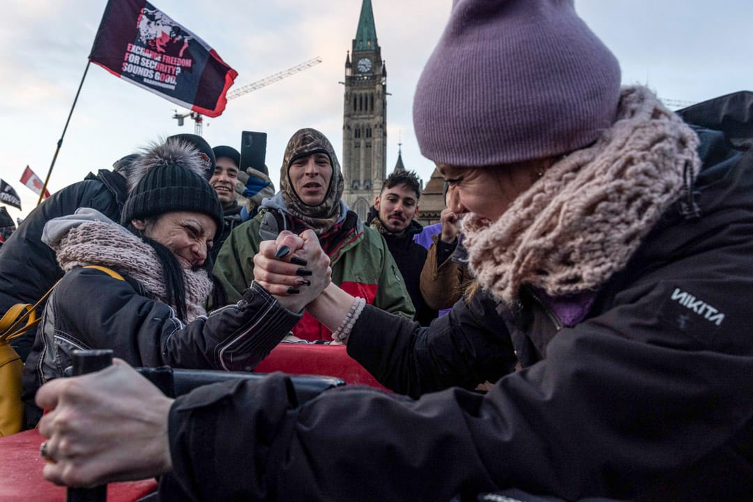 2022年1月30日,加拿大首都渥太华,两名反疫苗示威者在国会山庄外拗手瓜。