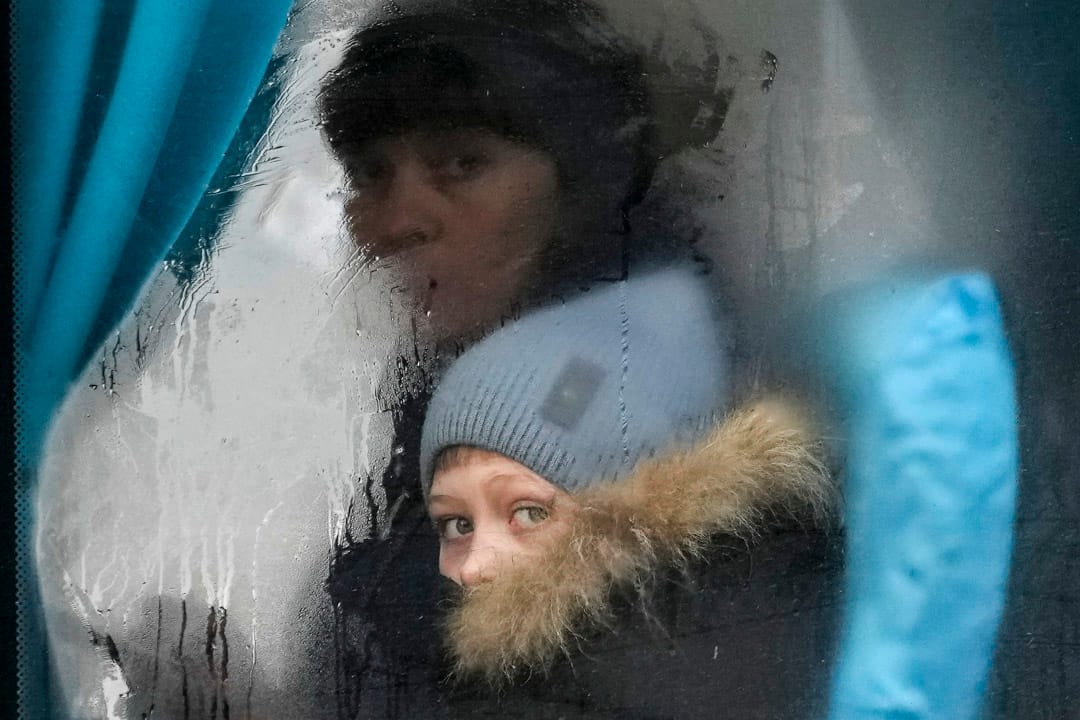 2022年2月24日，一名女士和女童坐车离开乌克兰东部的卢甘斯克地区，二人凝视著窗外。