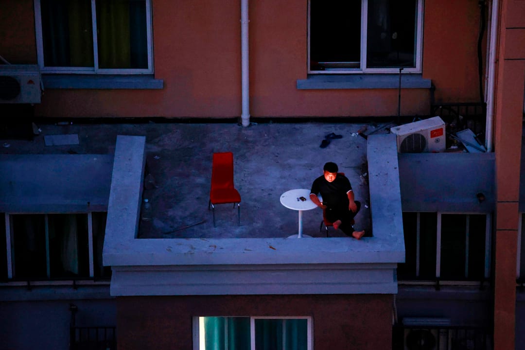 2022年4月11日,上海,一名男子在住宅區的陽台上看著他的智能手機。