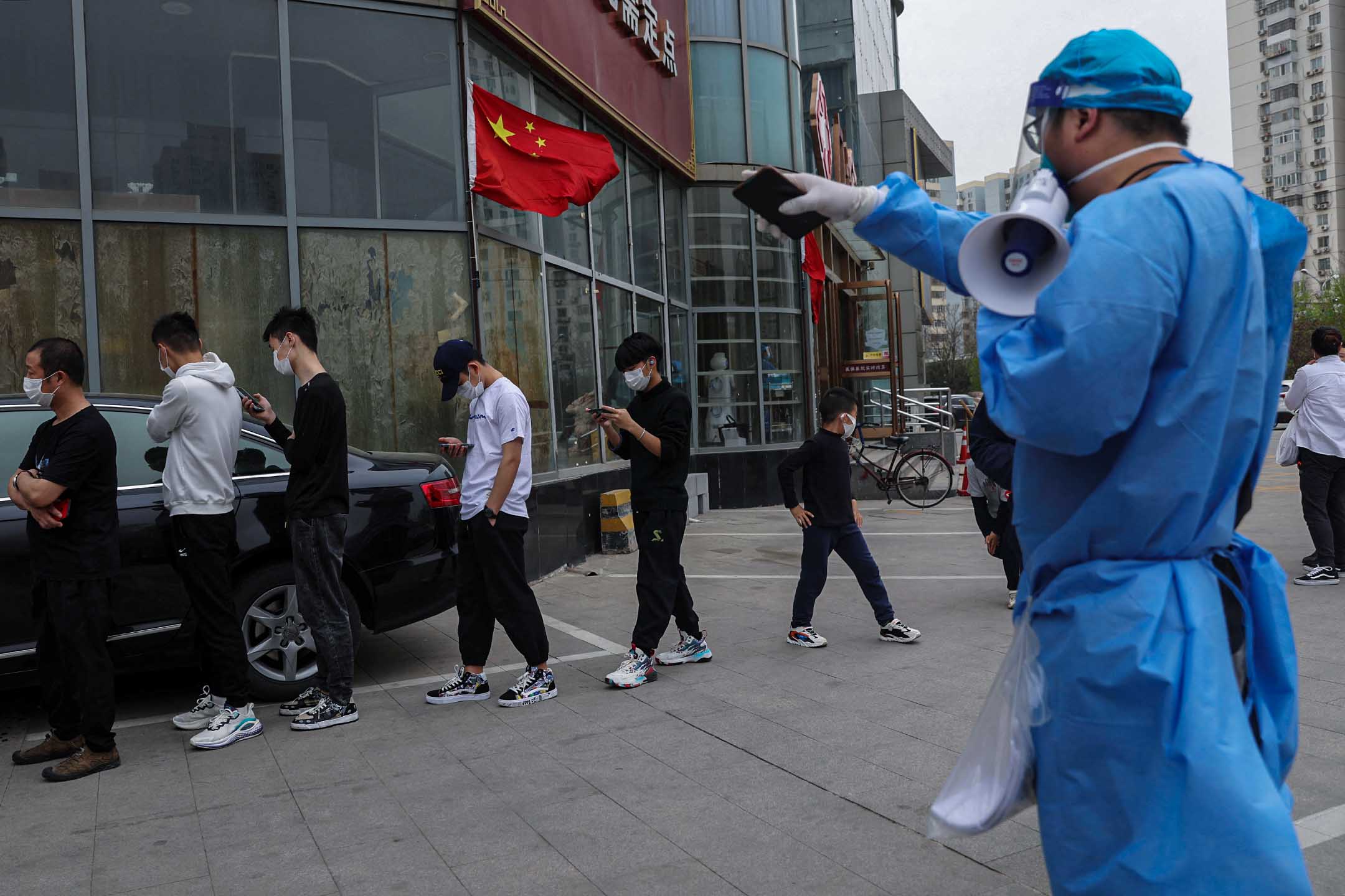 2022年4月11日,中國北京,一名工作人員引導市民在檢測點排隊進行核酸檢測。