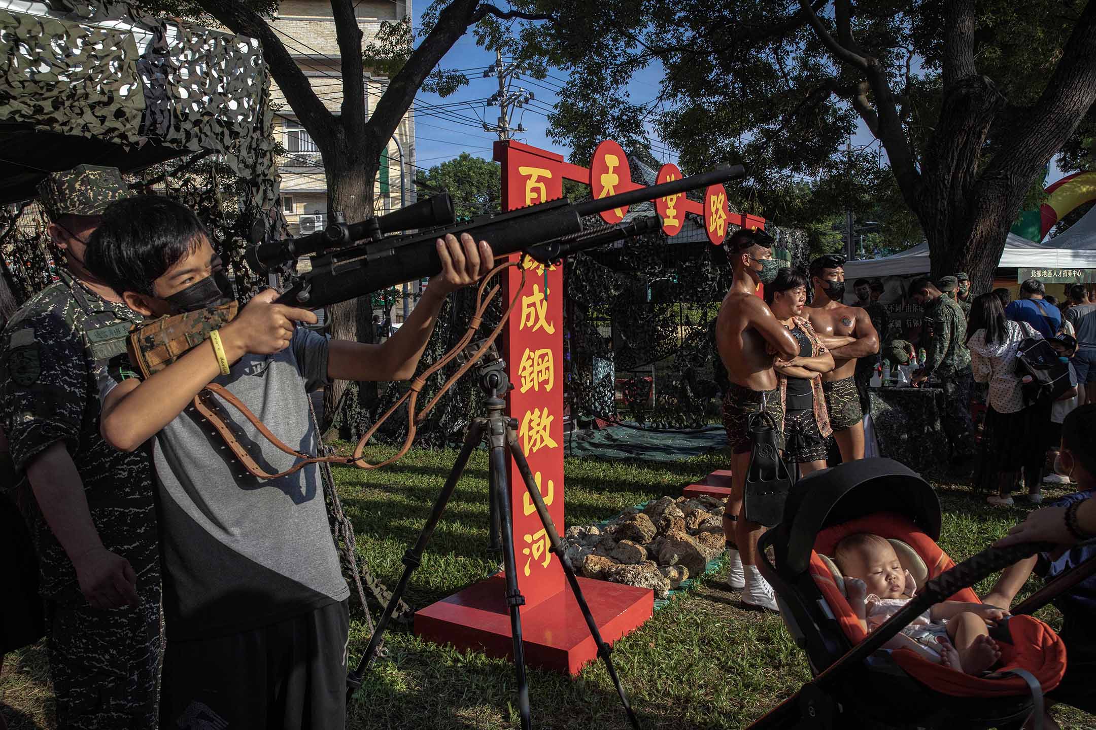 2022年9月17日，為強化全民國防，國防部在桃園馬祖文創園區舉辦「進擊的迷彩」活動，市民拿著槍觀看。攝：陳焯煇/端傳媒