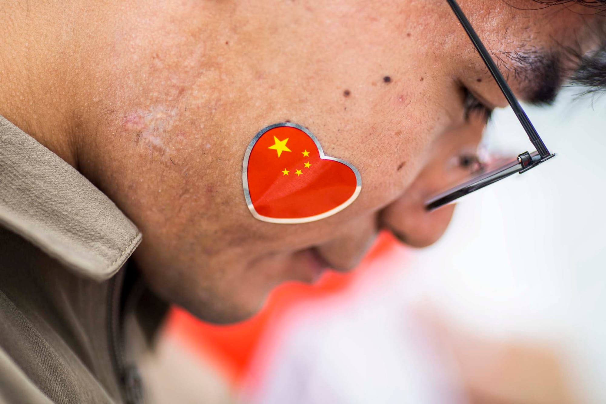 2023年7月1日,尖沙咀,一名旅客脸上贴上国旗。摄:陈焯煇/端传媒