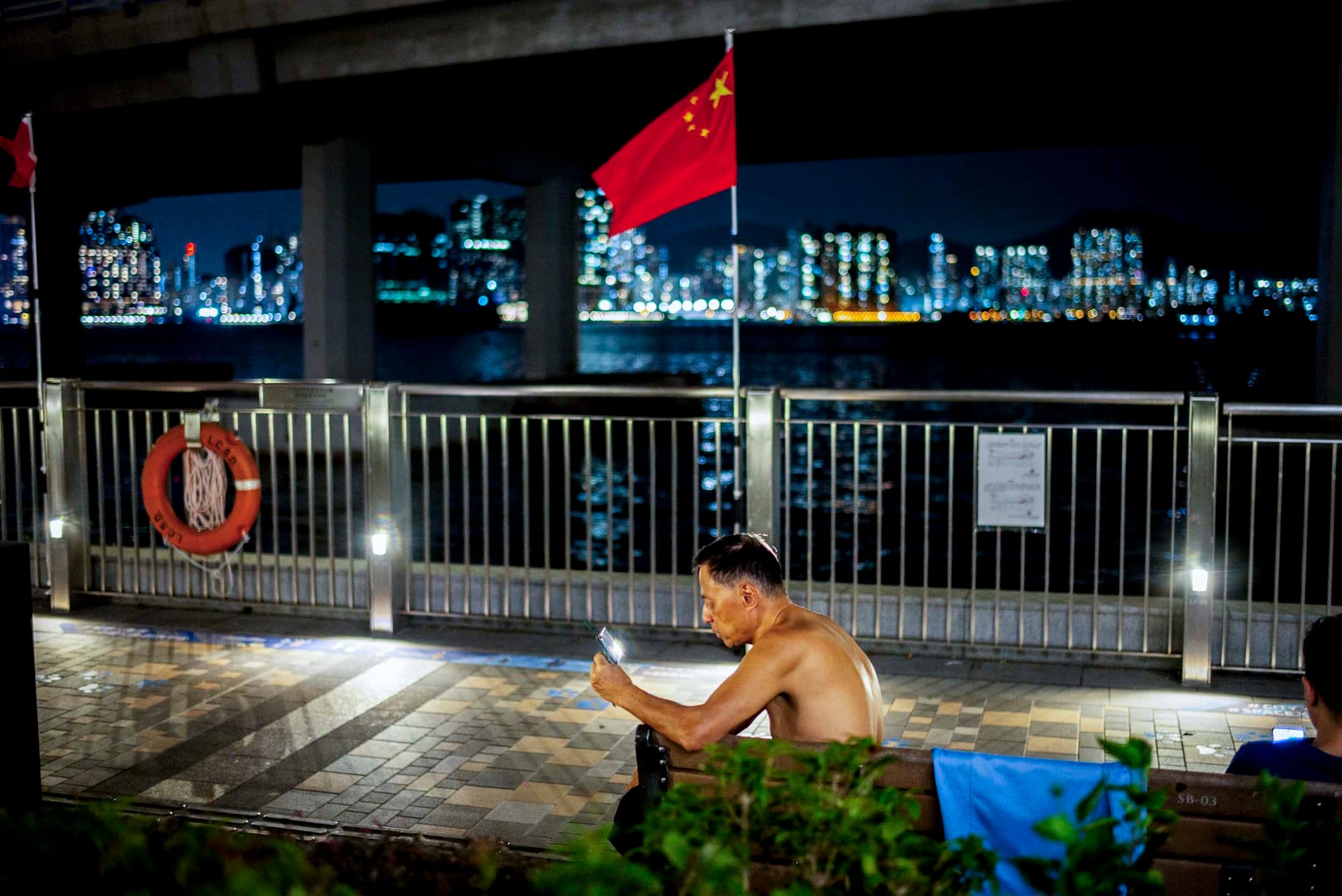 北角碼頭,一位脫去上衣的男士觀看手機。攝:林振東/端傳媒