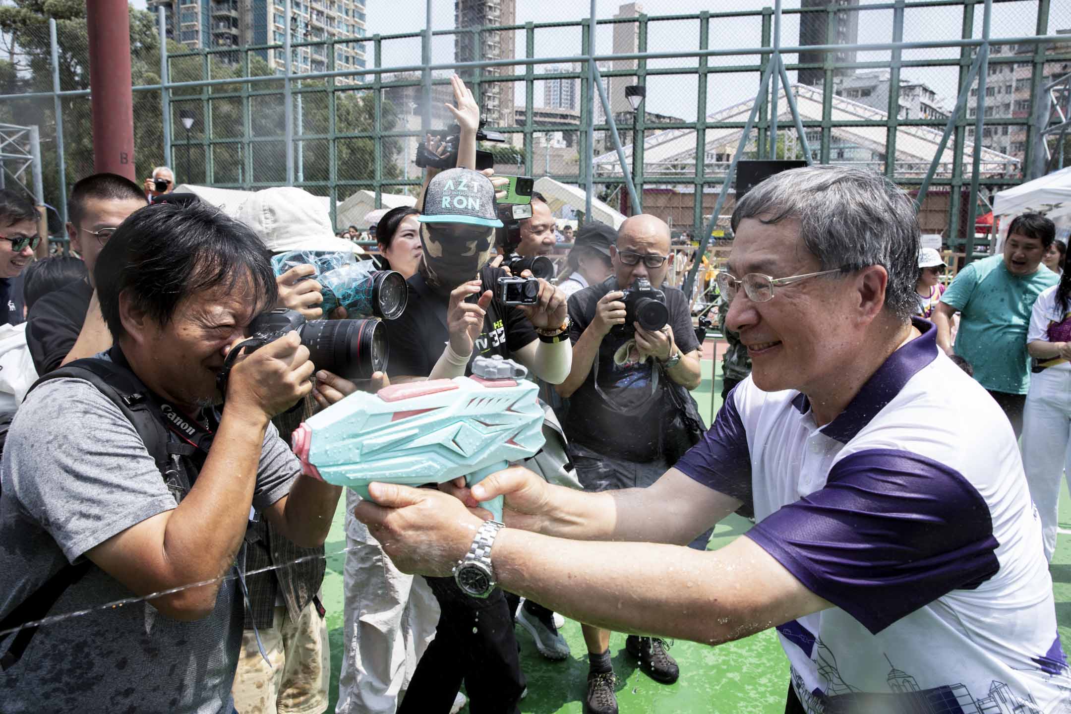 2024年4月13日,政务司副司长卓永兴到篮球场与市民互相射水,期间有小朋友以水枪“追击”卓永兴。摄:林振东/端传媒