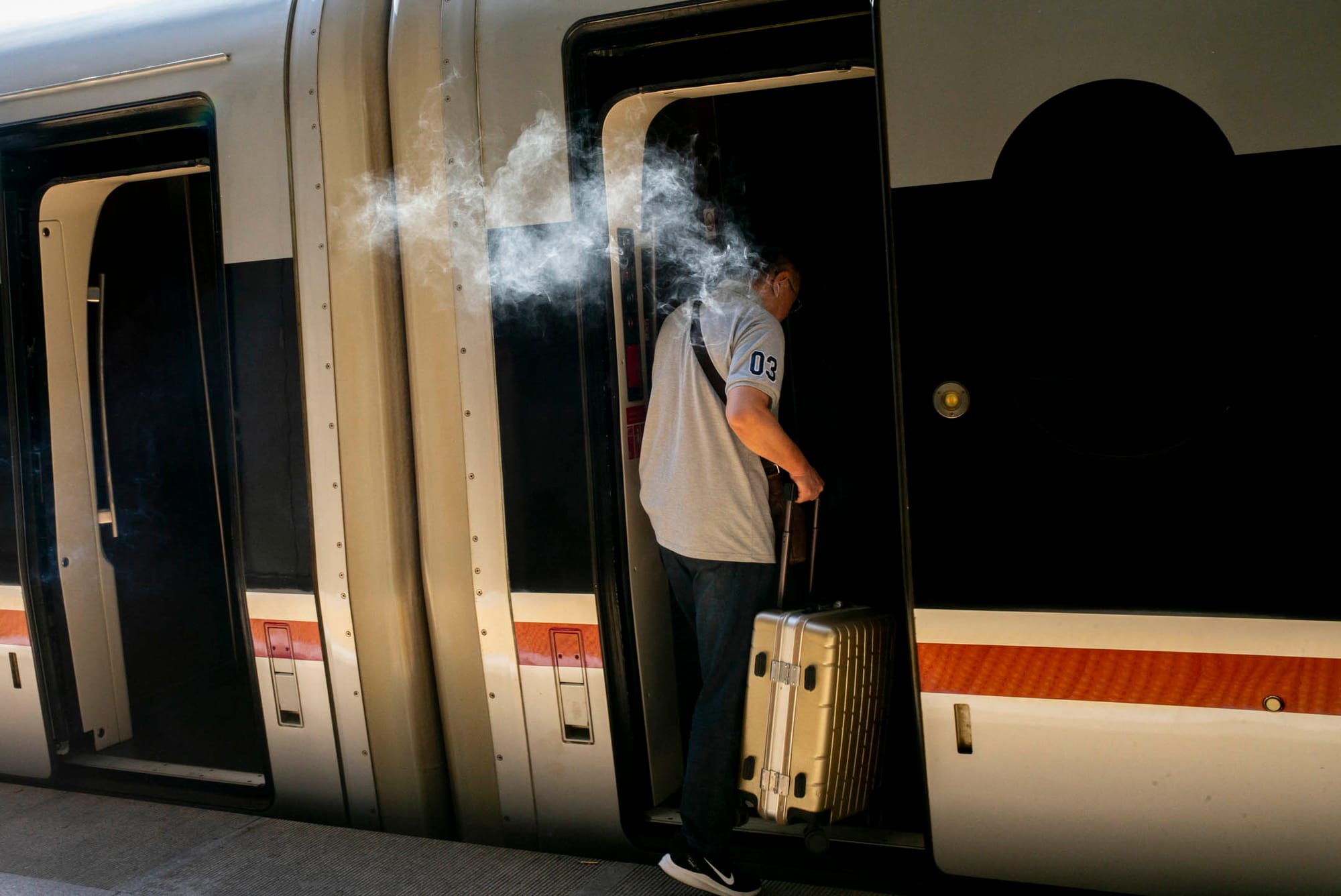 2023年8月29日，中國北京西站高鐵月台，一名乘客登上開往河北的高鐵前，抽最後一口煙。攝：林振東/端傳媒