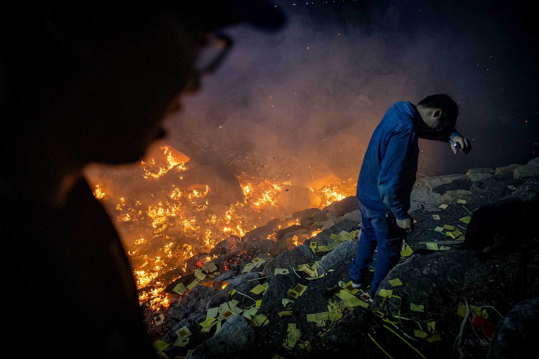 2024年8月17日，鸡笼中元祭，人们于八斗子望海巷放水灯前烧金纸。摄：陈焯煇/端传媒