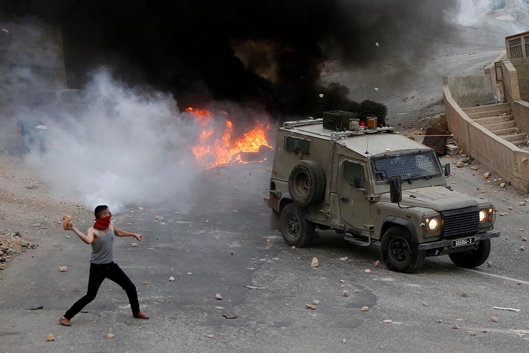 2015年10月6日，約旦河西岸，巴勒斯坦青年向以色列軍車投擲石頭。攝：Majdi Mohammed/AP