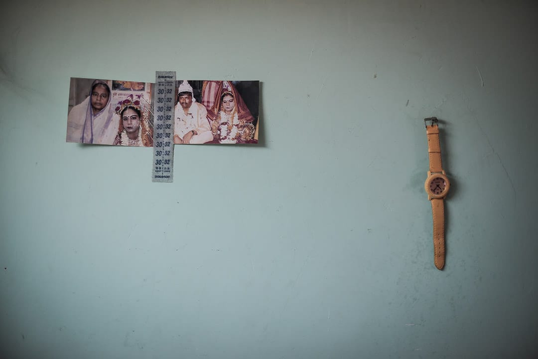 2013年，一位尋求庇護者家中牆上的佈置，包括以前的結婚照，以及一隻手錶。攝: Billy H.C. Kwok/ 端傳媒