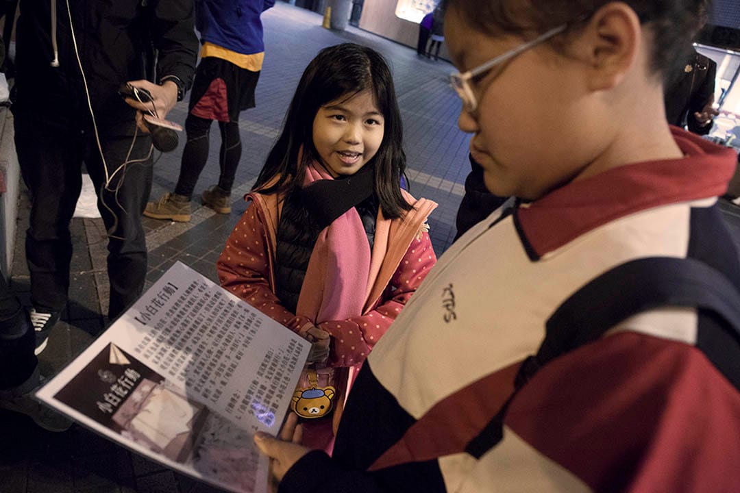 年輕的參與者正向途人介紹製作小白花活動衣飾的理念。攝:陳國誠/端傳媒