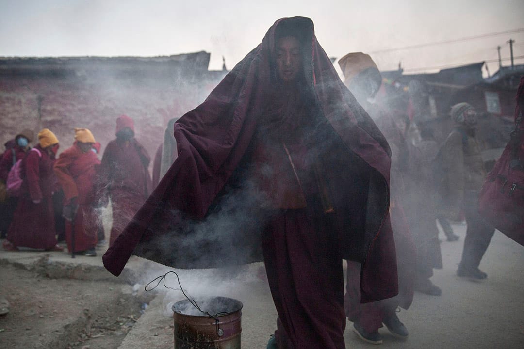 10月31日早上,色達喇榮五明佛學院,一名喇嘛在煙霧中穿過。攝:Kevin Frayer/Getty Images